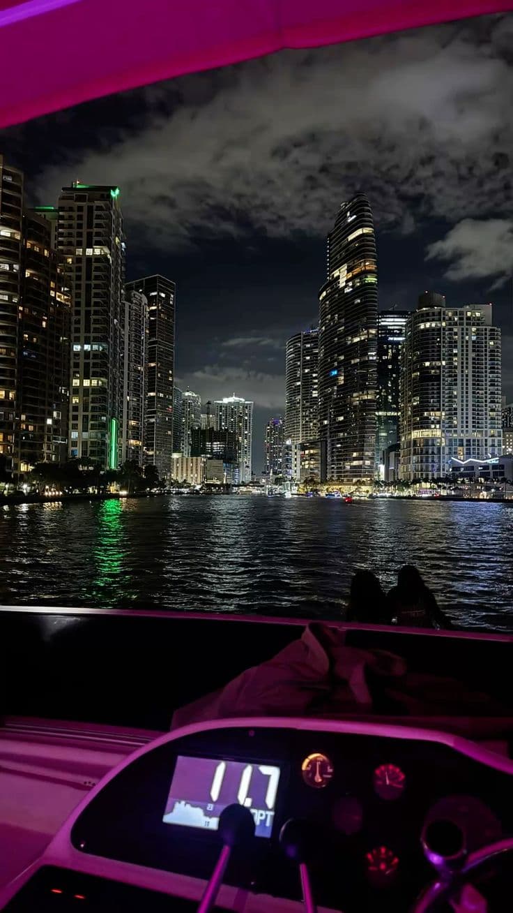 the city skyline is lit up at night as seen from a boat in the water