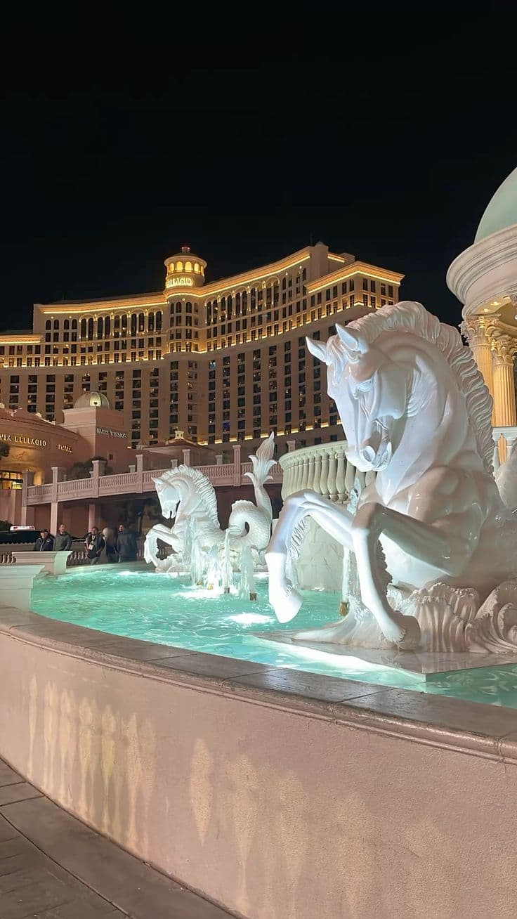 the fountains are lit up at night in front of the hotel and casino buildings,