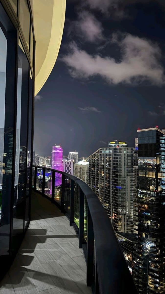 the city skyline is lit up at night with skyscrapers in the foreground and clouds in the b