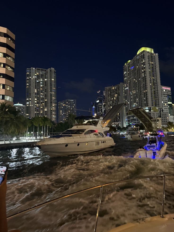 a boat is traveling through the water in front of some tall buildings at night time