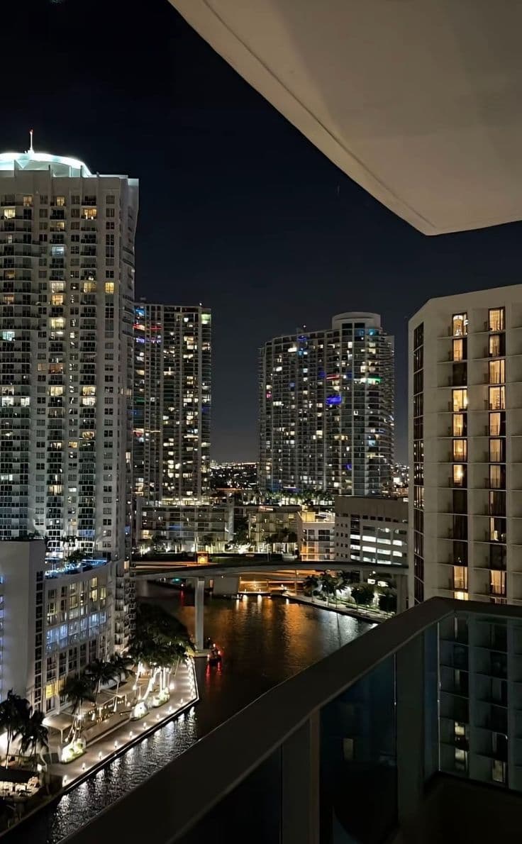 the city lights shine brightly at night in this view from an apartment building's balcony