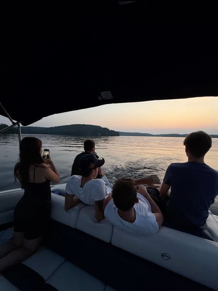 Group of young friends relaxing on a boat at sunset