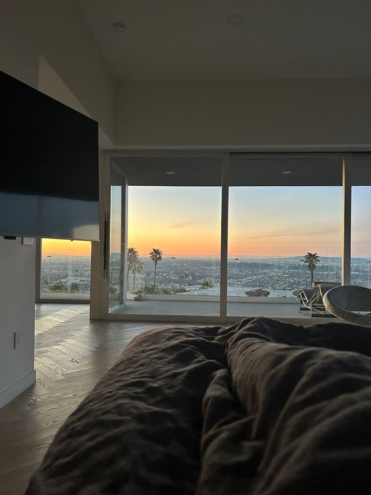 a bedroom with large windows overlooking the city