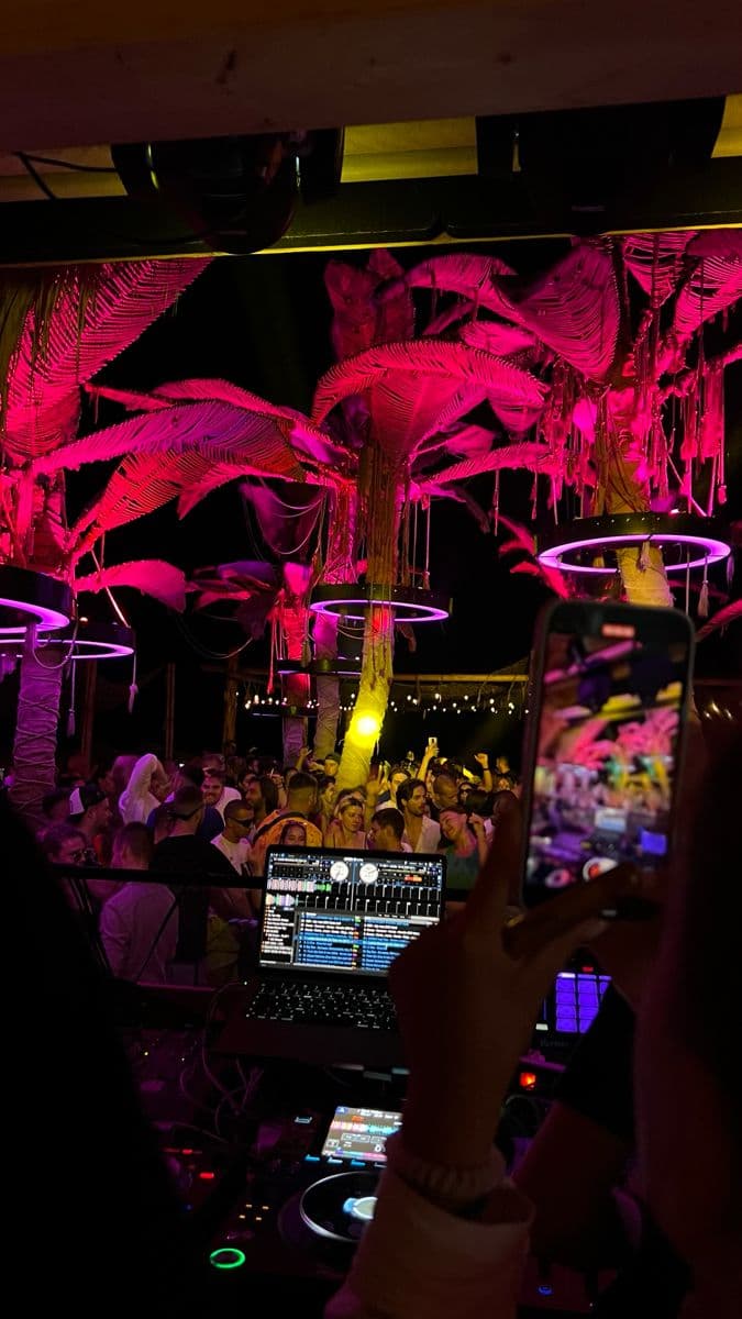a person holding up a cell phone in front of a room full of lights and plants