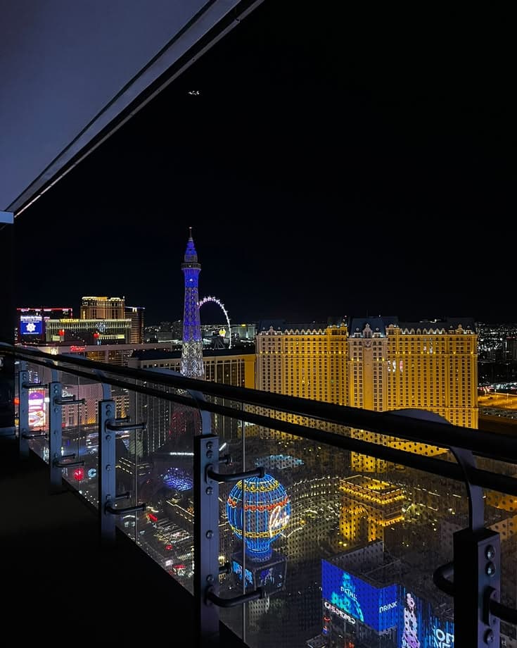 a balcony overlooking the las vegas strip at night with buildings lit up in the background