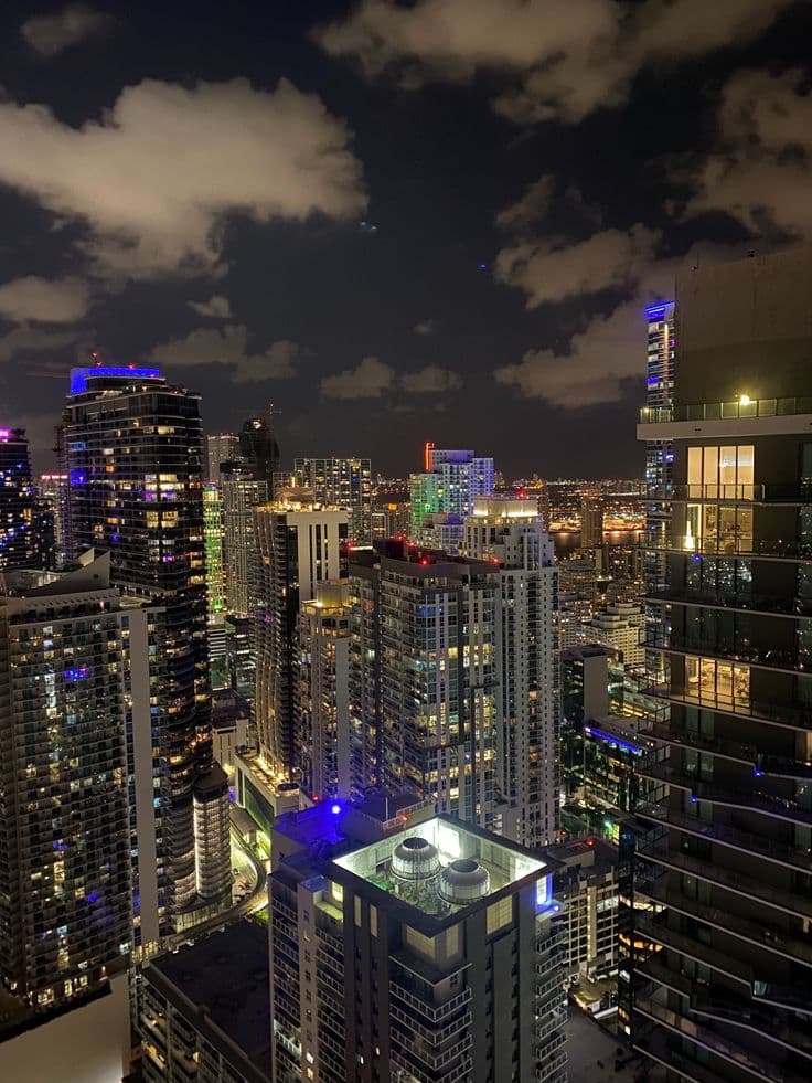 the city skyline is lit up at night, with skyscrapers in the foreground