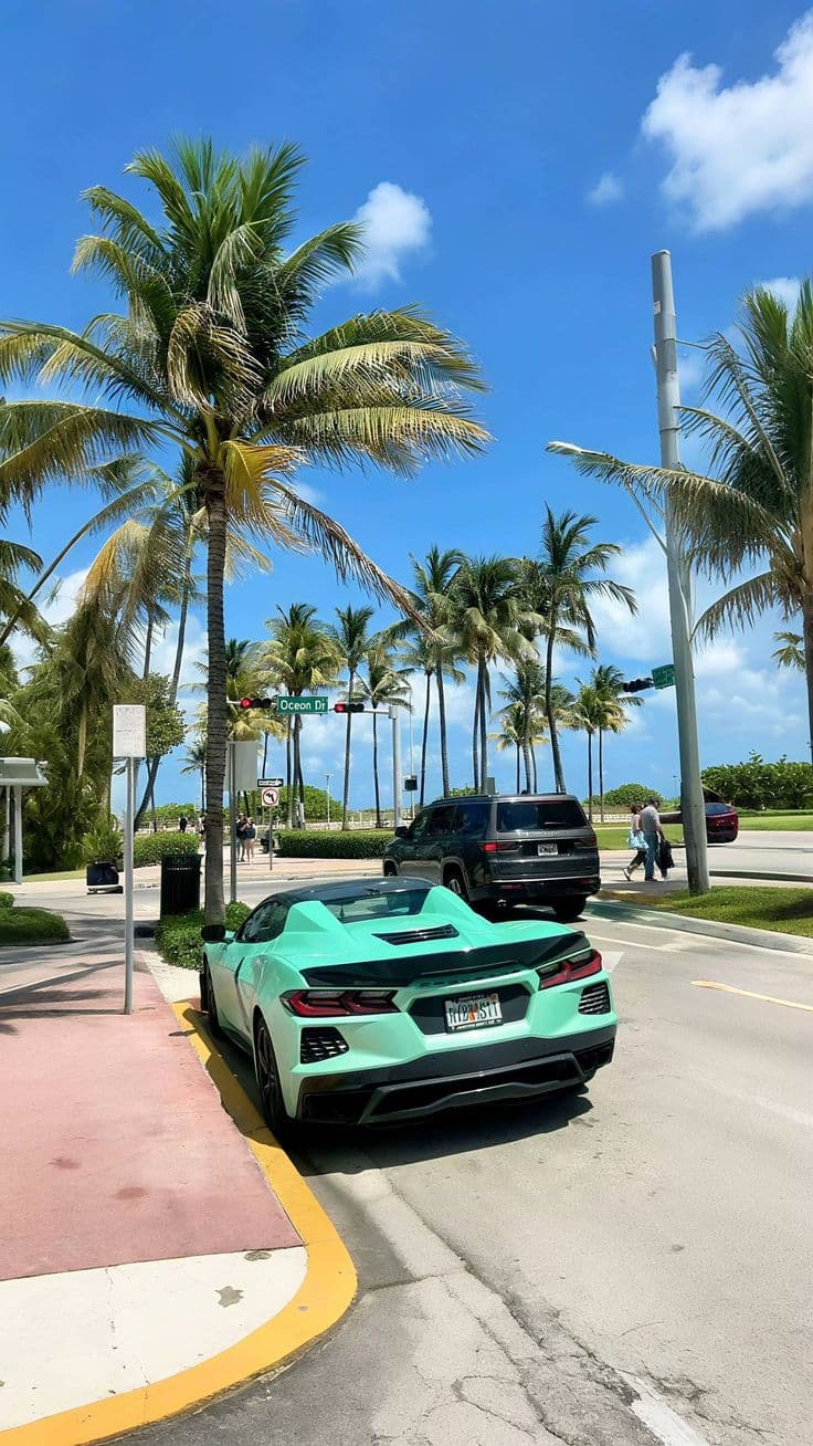 two green sports cars parked on the side of the road in front of palm trees