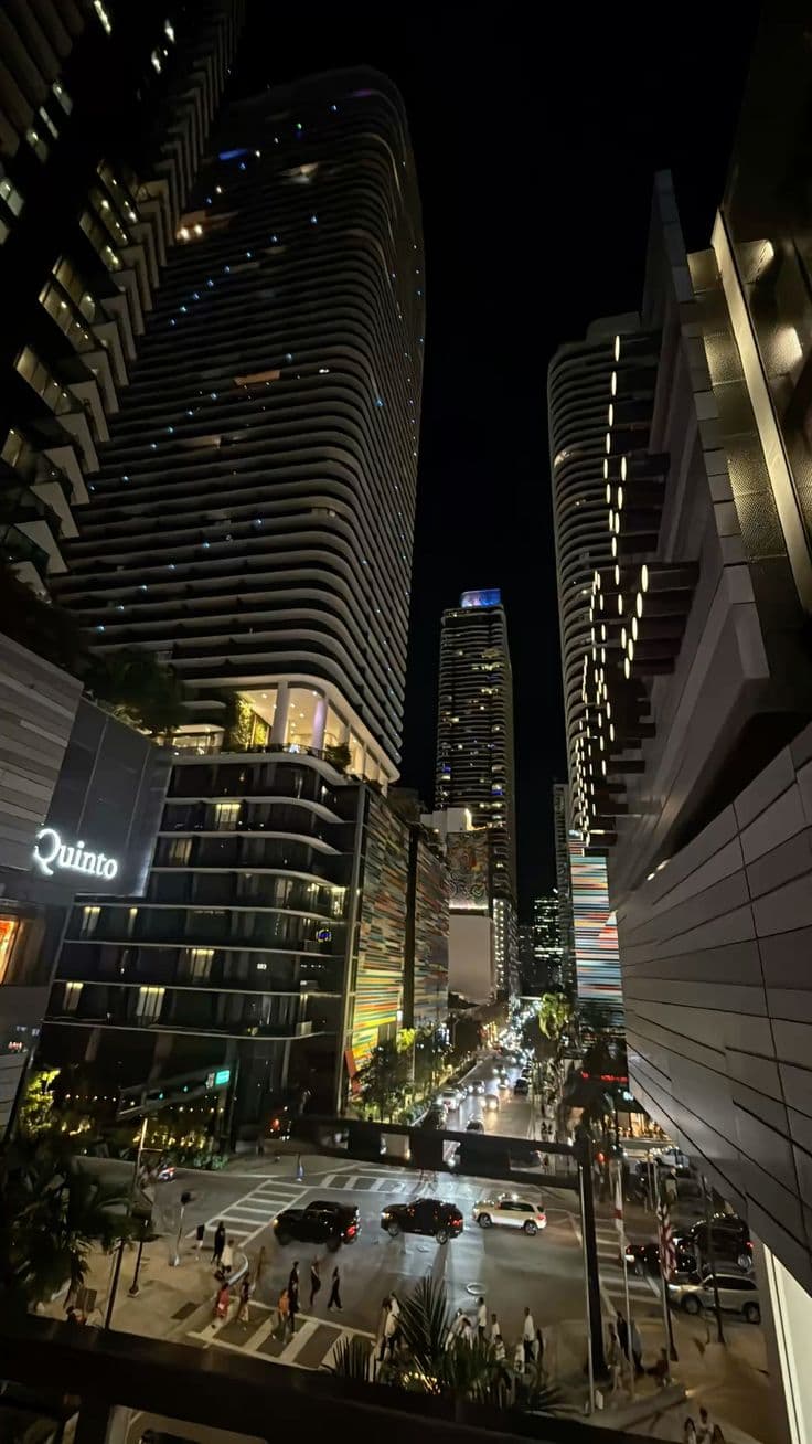 the city is lit up at night and it looks like there are cars driving down the street