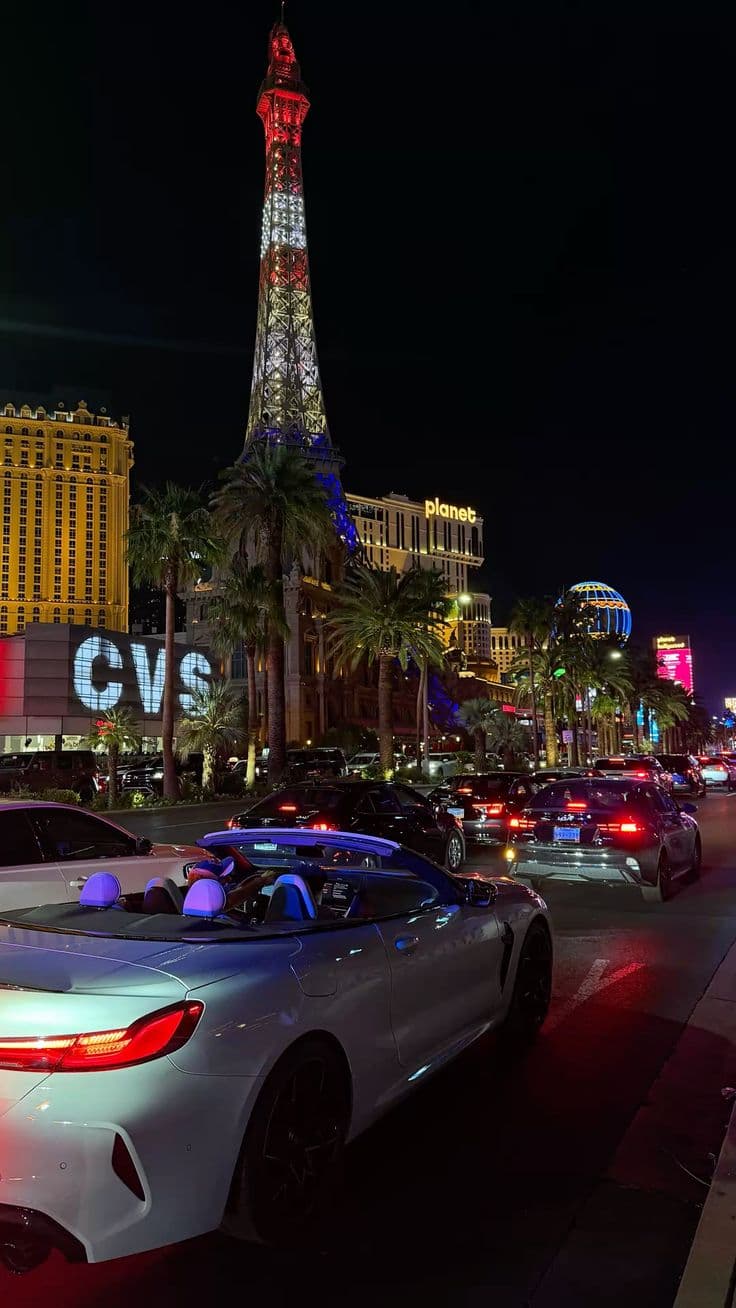 cars are parked in front of the eiffel tower and las vegas hotel at night