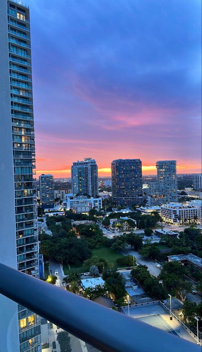 the city skyline is lit up at dusk from an apartment balcony in miami, florida