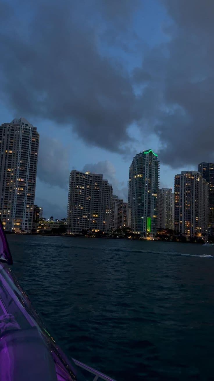 the city skyline is lit up at night as seen from a boat in the water
