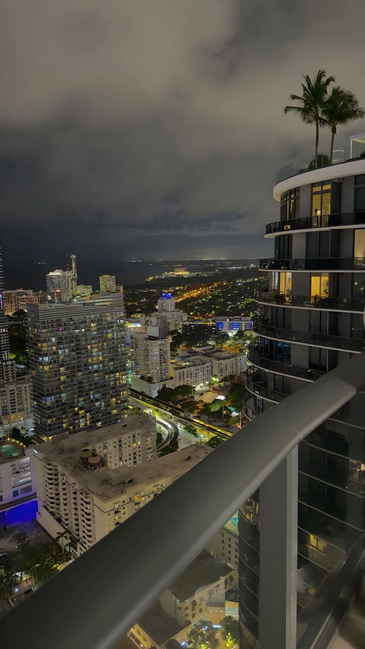 the city lights shine brightly in the distance from an apartment balcony at night with dar
