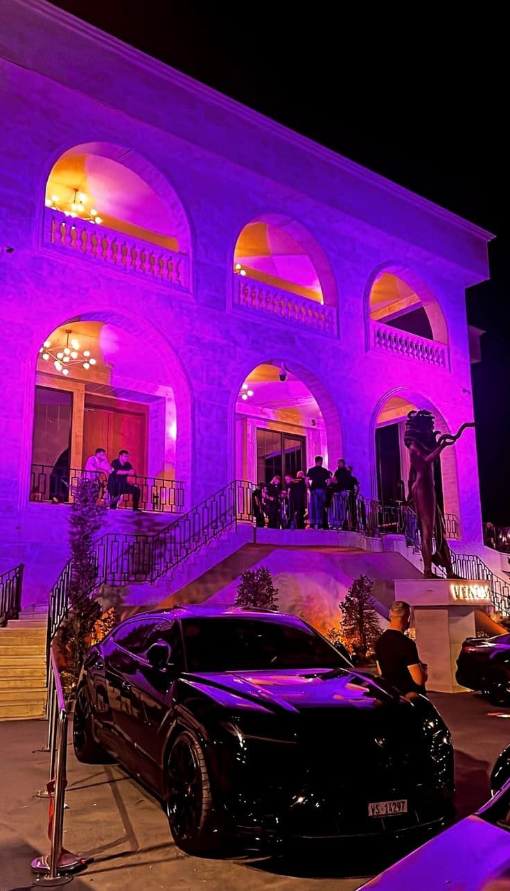 a black car parked in front of a building with purple lighting on it's windows
