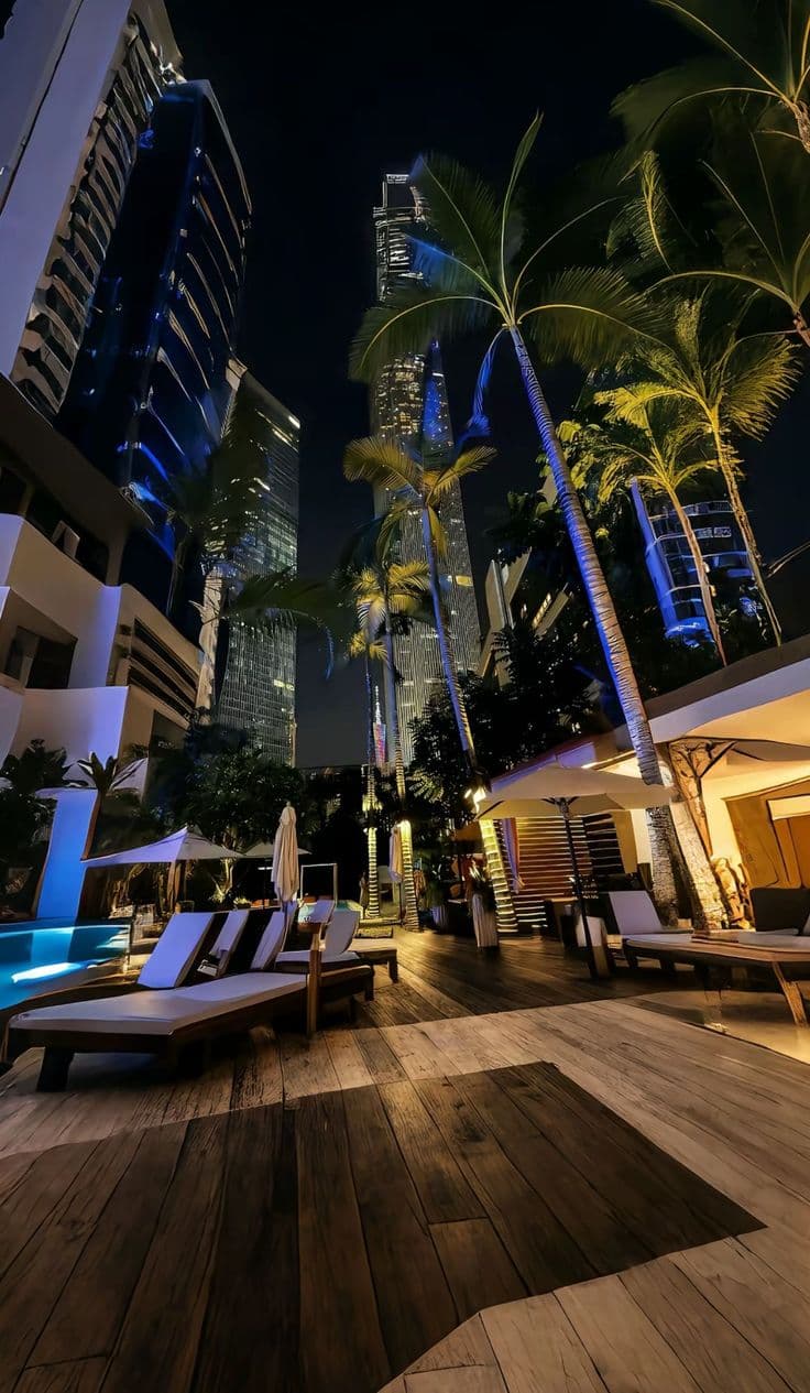an outdoor pool with lounge chairs and palm trees in the background at night, surrounded b