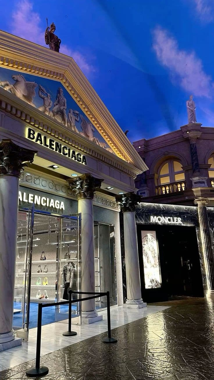 the entrance to an upscale shopping mall at night with blue sky in background and white co